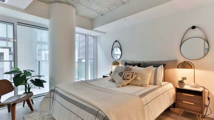 A minimalist cozy white bedroom featuring a comfortable bed with a plush mattress topper for added softness and support.