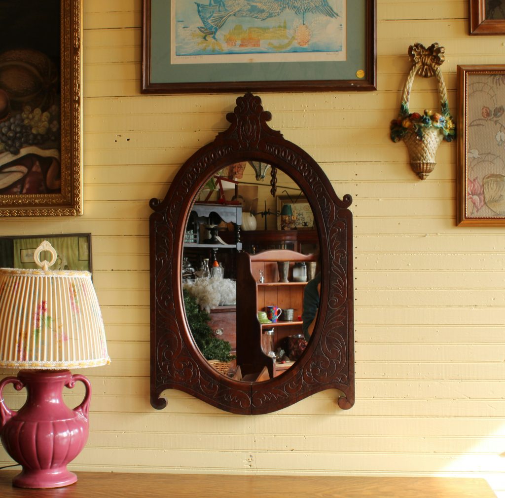 Round distressed wood mirror reflecting natural light in a farmhouse living room