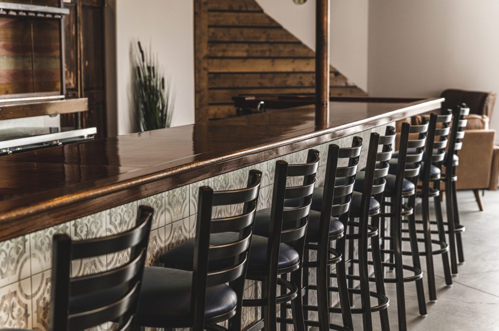 Affordable and stylish bar stools under $100 lined up along a modern kitchen island