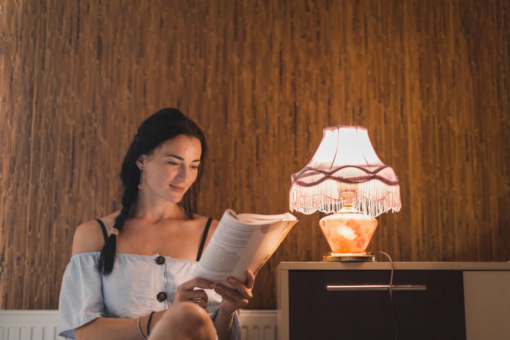 Cozy reading nook with warm lighting, armchair, and floor lamp by the window.