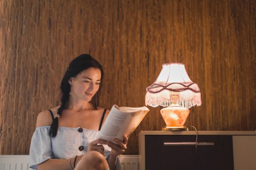 Cozy reading nook with warm lighting, armchair, and floor lamp by the window.