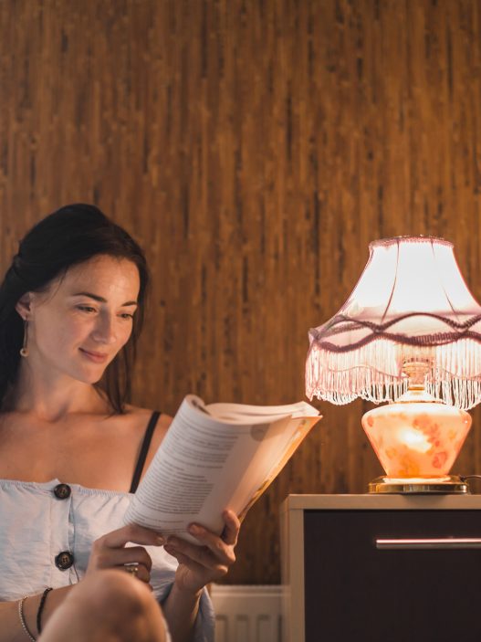 Cozy reading nook with warm lighting, armchair, and floor lamp by the window.